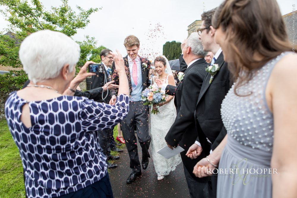 Unobtrusive wedding photography Surrey Wedding guests throw confetti on wedding day in Surrey