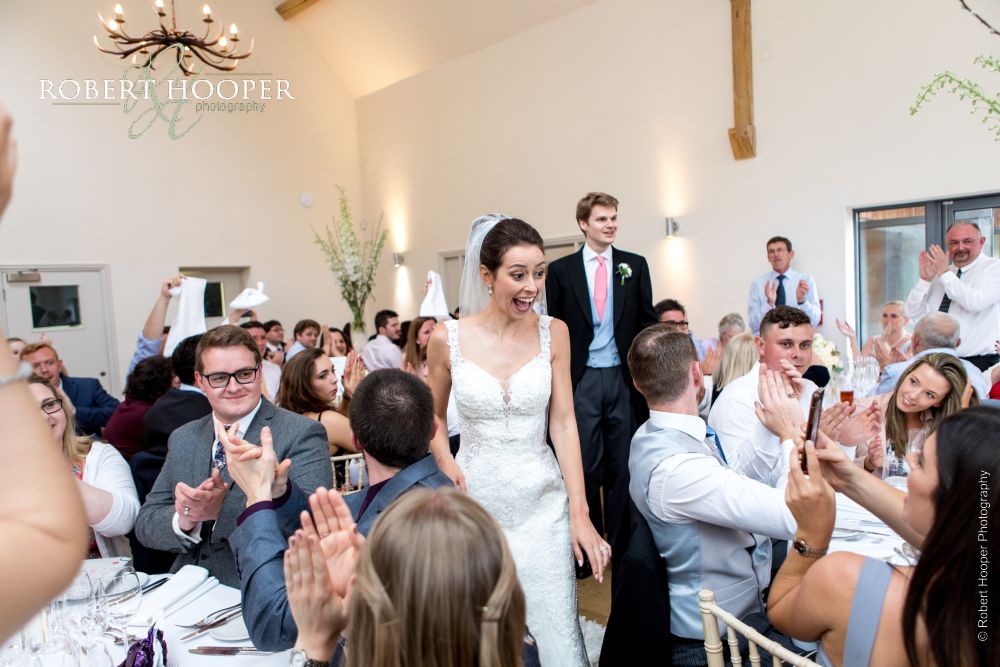 Candid wedding photographer Millbridge Court Guests clapping bride and groom's entrance to wedding breakfast at Millbridge Court Surrey